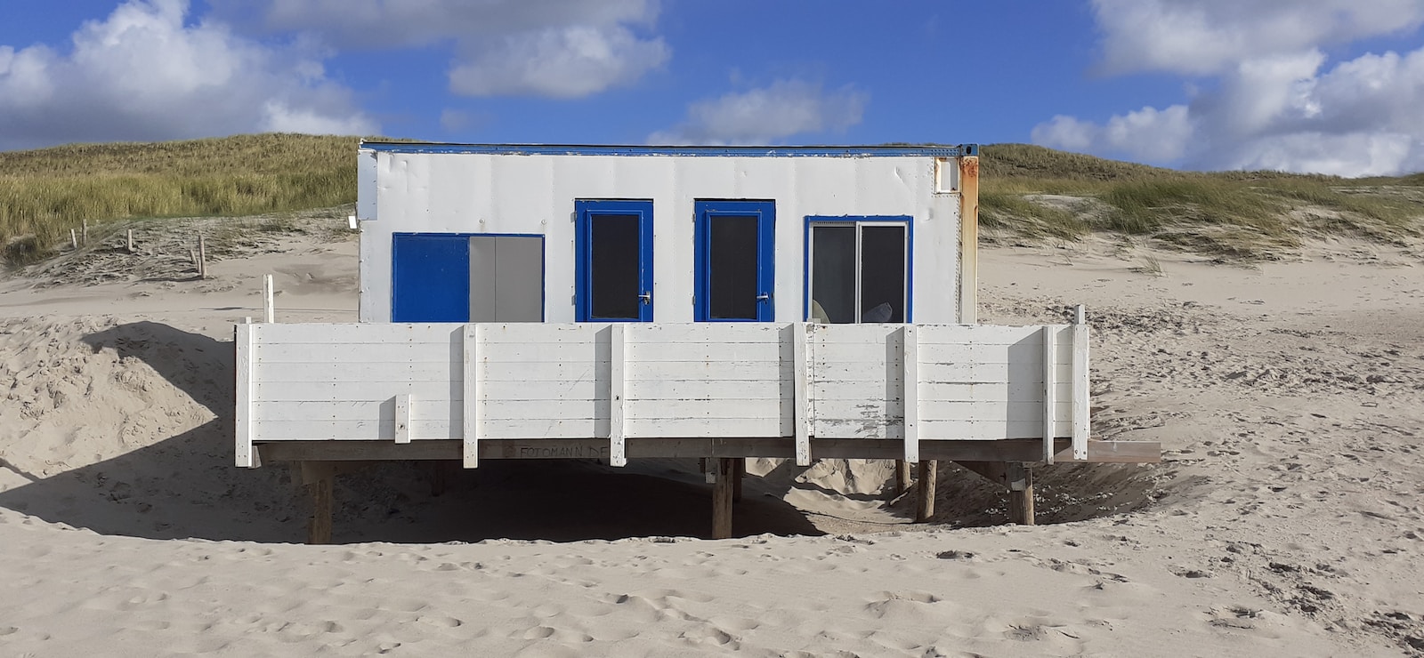 white and blue wooden house near green field under blue and white skies